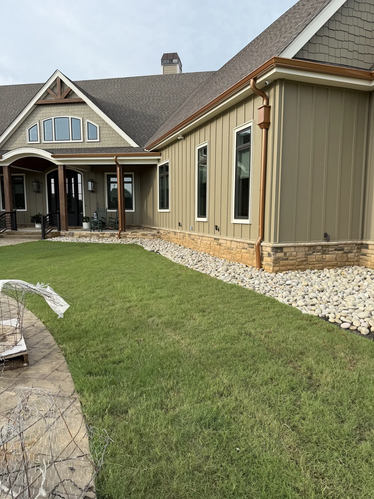 New sod installed beside a home and a river-rock border