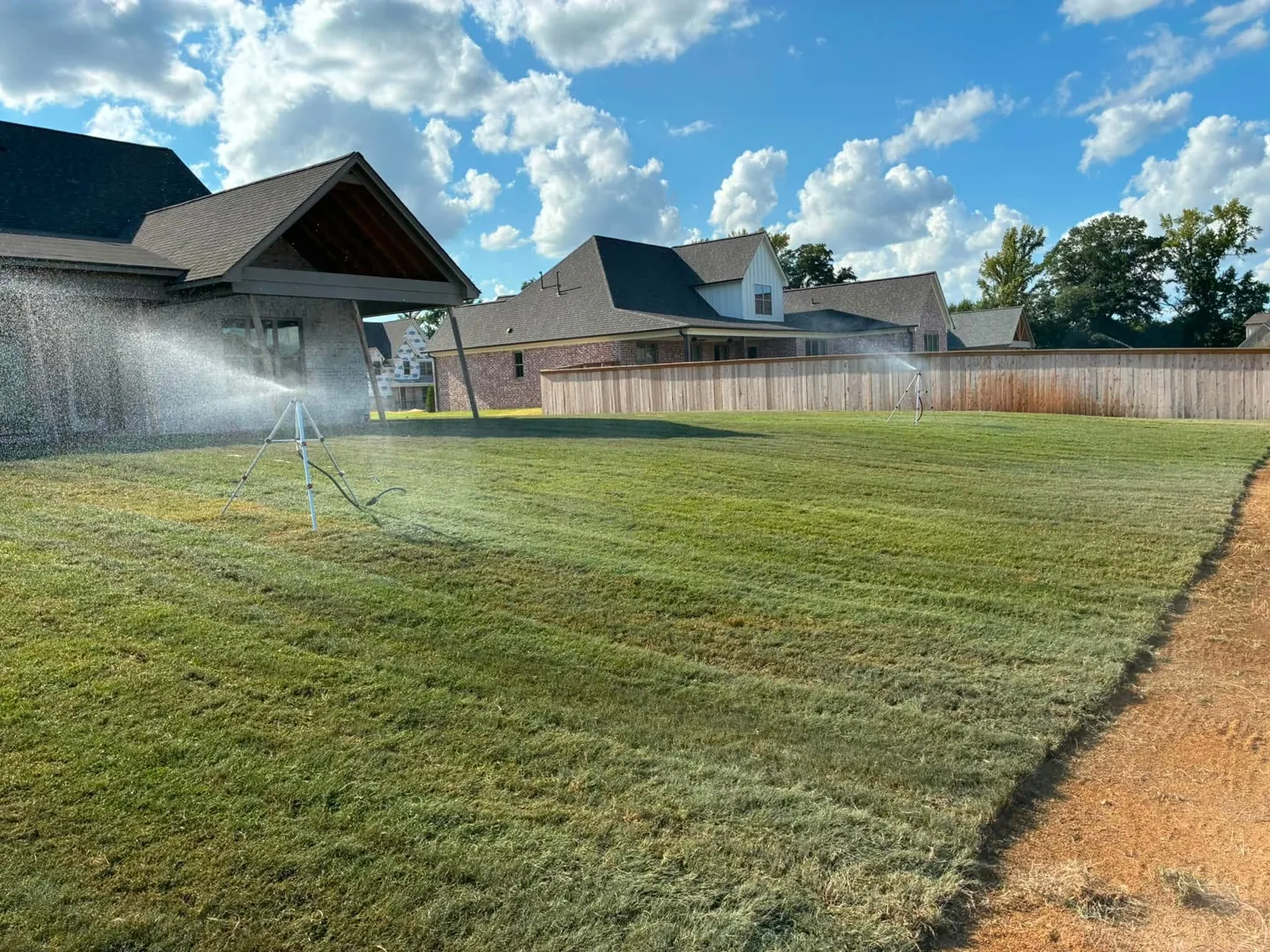 Sprinkler watering freshly installed sod outside new homes