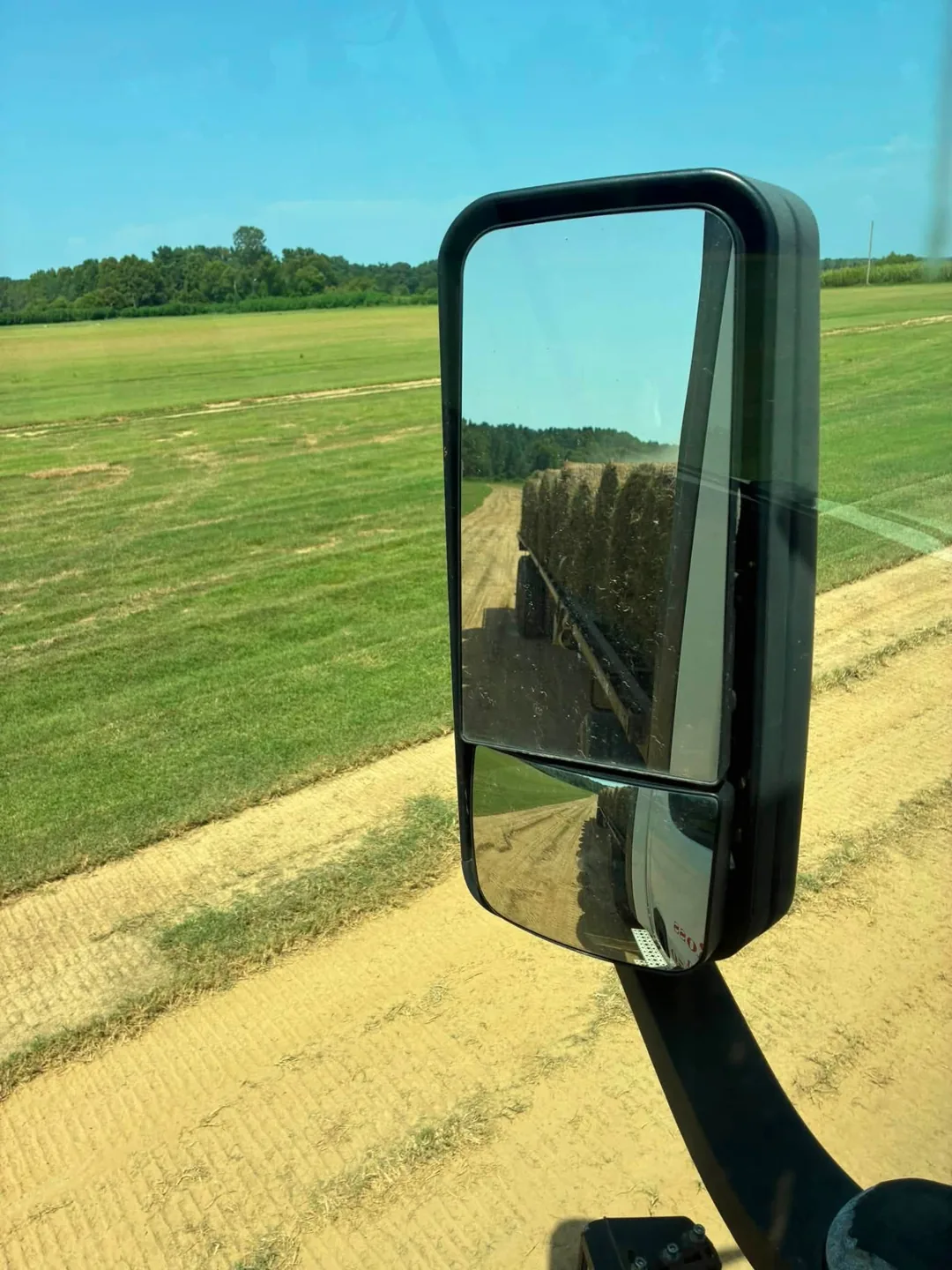 Sod field and harvested rows viewed beside a truck mirror