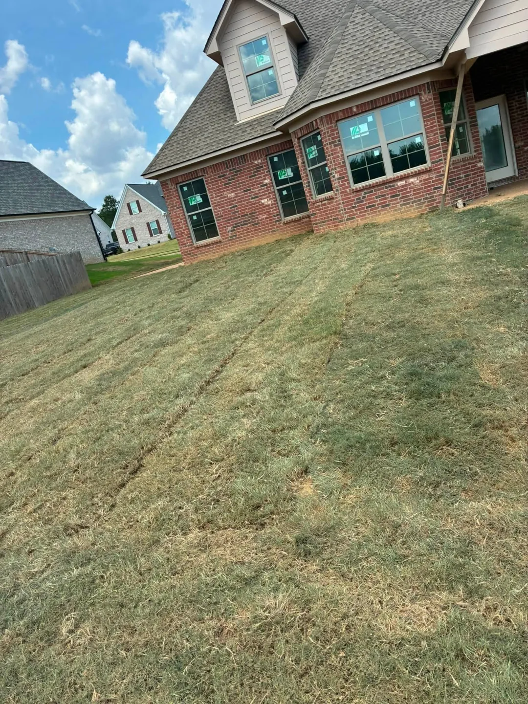 New sod across the front of a brick house with a steep roof